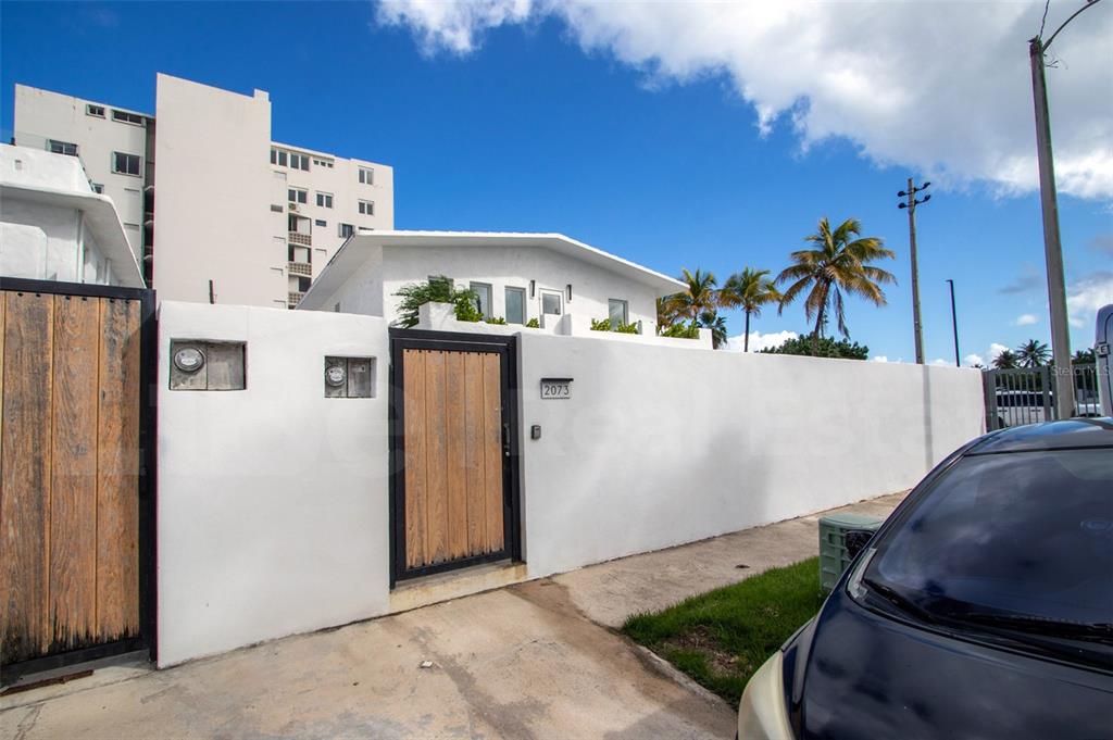 A white walled exterior with a wooden gate and a car parked in the foreground — 2073 CACIQUE STREET, SAN JUAN, PR