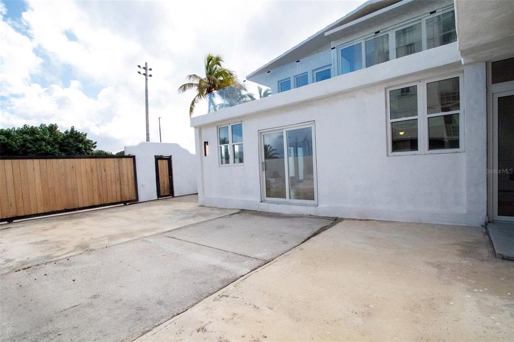 A white exterior wall features a sliding glass door, windows, and a concrete patio area — 2073 CACIQUE STREET, SAN JUAN, PR