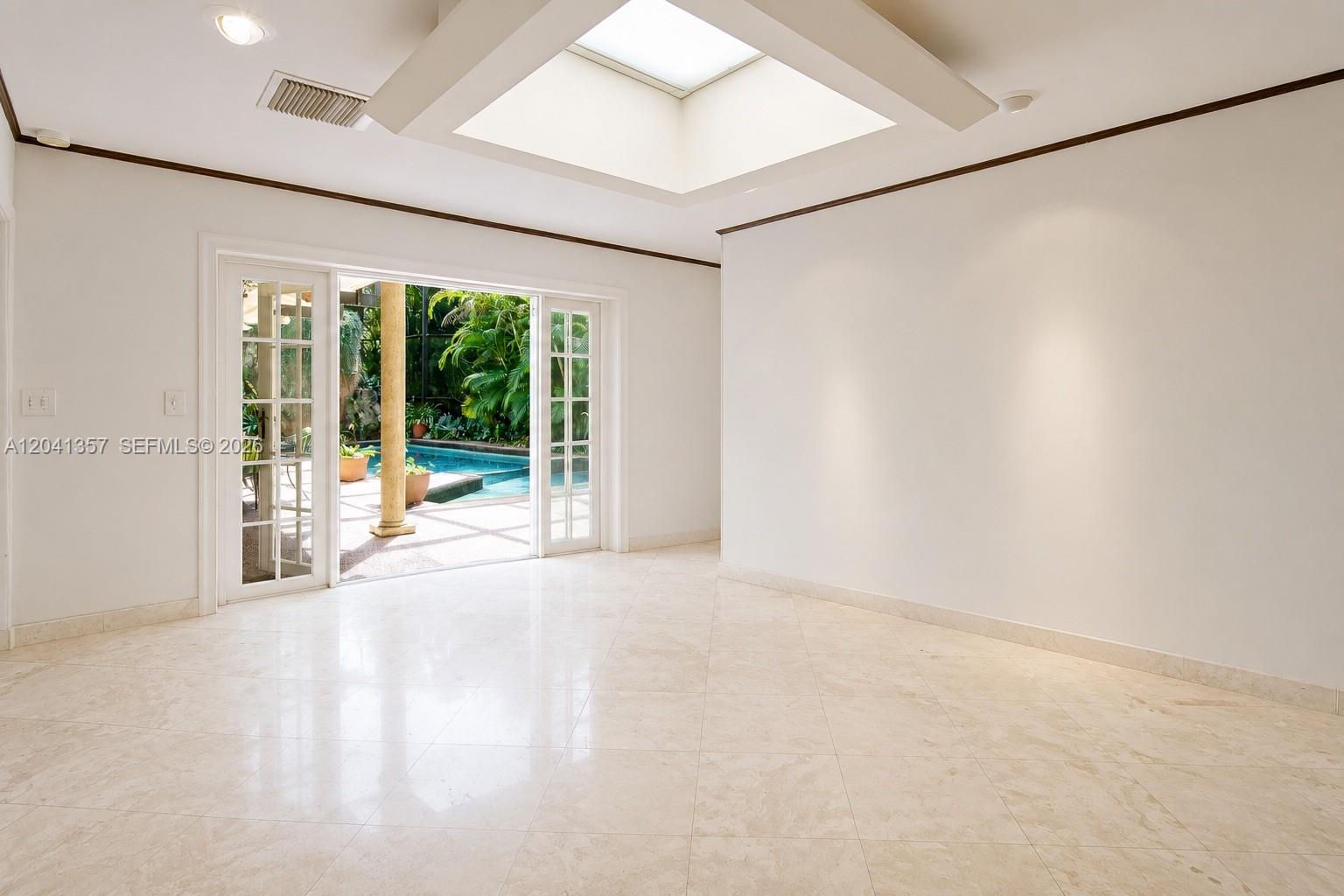 A bright, empty room with tile floors, a skylight, and glass doors opening to a pool — 3441 Poinciana Ave, Miami FL 33133, MIAMI, FL