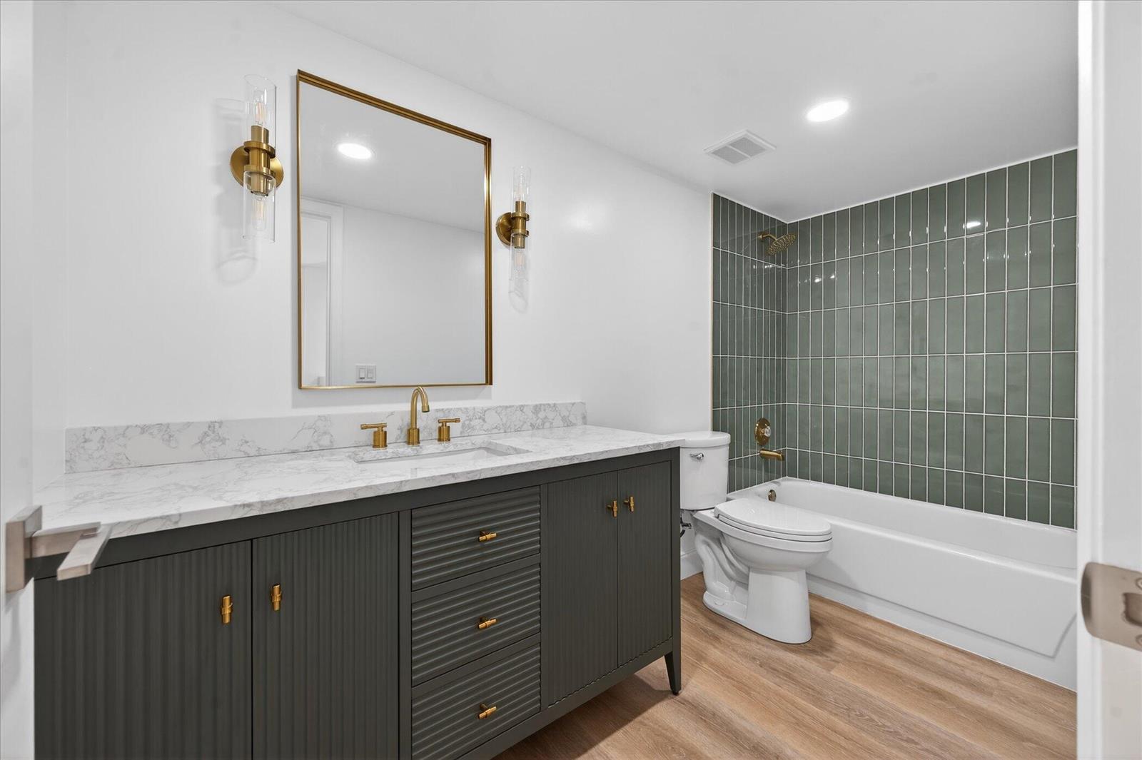 A bathroom features a dark gray vanity, marble countertop, gold fixtures, and green tiled shower — 1617 16th Way, West Palm Beach FL 33407, WEST PALM BEACH, FL