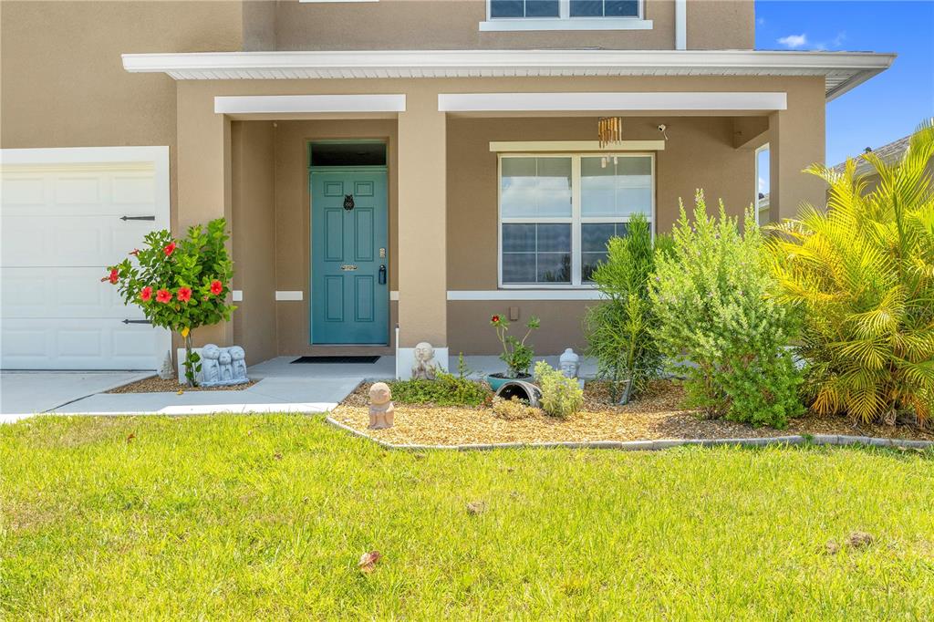 The exterior of a house features a teal front door, a garage, and landscaping — 204 INMAN BOULEVARD, WINTER HAVEN, FL