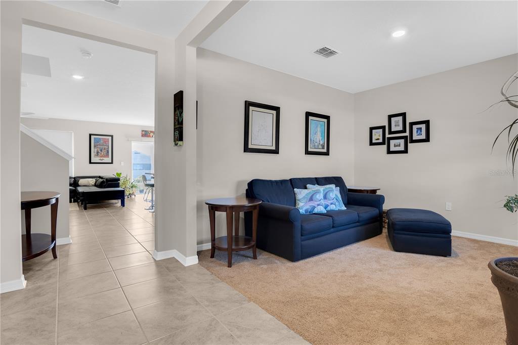 A living room features a blue sofa, a matching ottoman, and framed wall art — 204 INMAN BOULEVARD, WINTER HAVEN, FL
