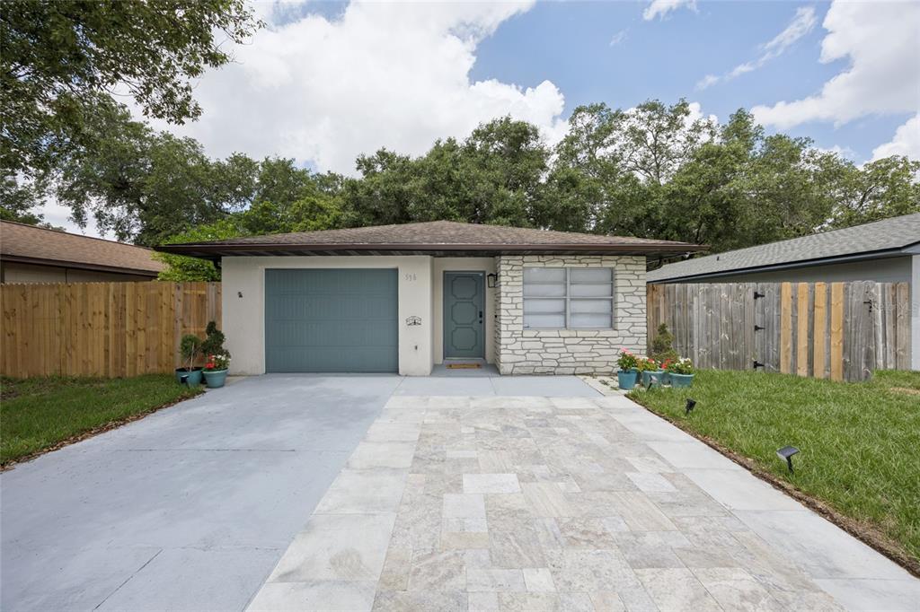 A single-story house features a stone facade, a gray garage door, and a paved driveway — 536 HIBISCUS WAY UNIT 7B, ORLANDO, FL