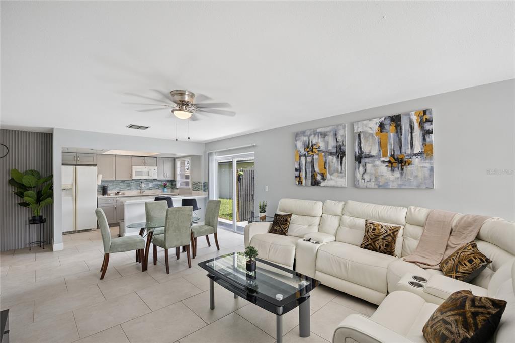 A living room with a white sectional sofa, glass coffee table, and an adjacent kitchen — 536 HIBISCUS WAY UNIT 7B, ORLANDO, FL