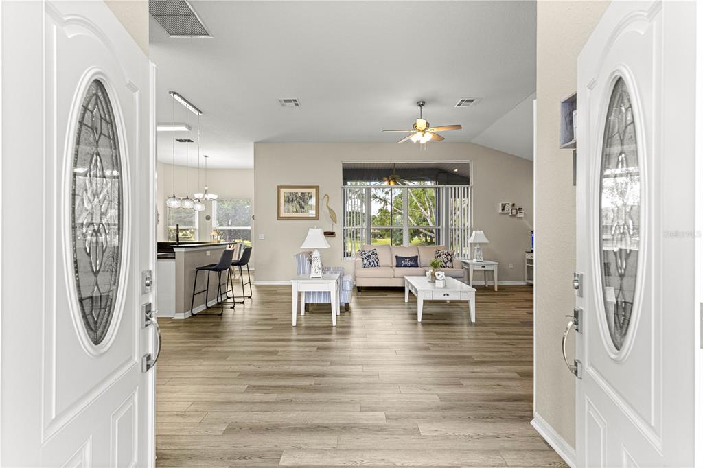 A view from an open front door into a living room with wood-look flooring — 6744 SW 113TH PLACE, OCALA, FL