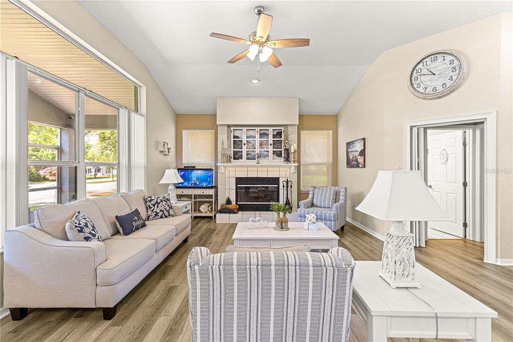 A living room features a fireplace, a beige sofa, striped armchairs, and wood-look flooring — 6744 SW 113TH PLACE, OCALA, FL