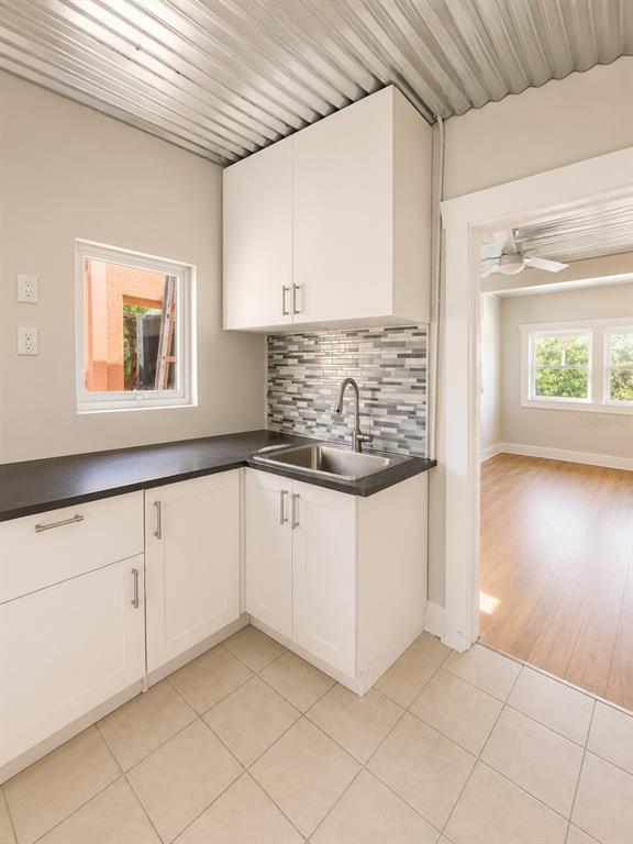 A kitchen area features white cabinets, a dark countertop, a sink, and a corrugated metal ceiling — 2316 N HIGHLAND AVENUE, TAMPA, FL