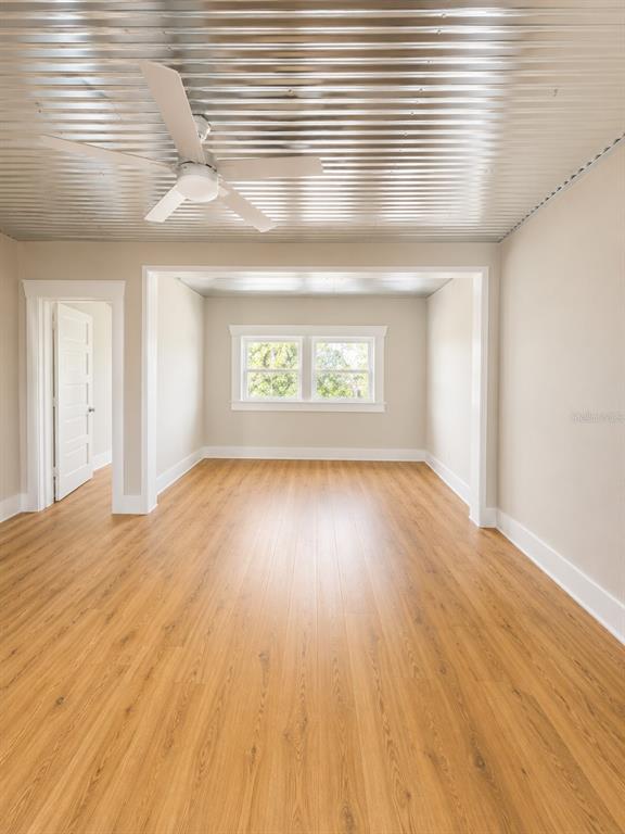 An empty room features light wood flooring, a corrugated metal ceiling, and a ceiling fan — 2316 N HIGHLAND AVENUE, TAMPA, FL