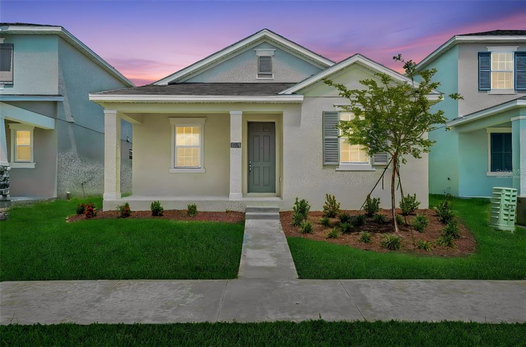 A single-story house with a covered front porch, gray door, and landscaped front yard — 5213 WAYPOINTE BOULEVARD, APOPKA, FL