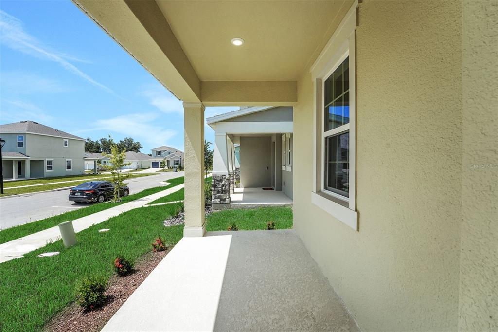 A view from a covered front porch looking out toward a suburban street and houses — 5213 WAYPOINTE BOULEVARD, APOPKA, FL