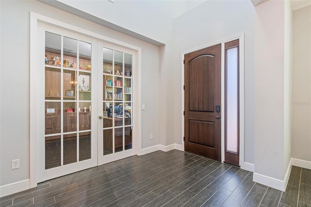 An entryway with dark wood-look tile flooring, a wooden front door, and glass-paneled double doors — 8324 LUDINGTON CIRCLE, ORLANDO, FL
