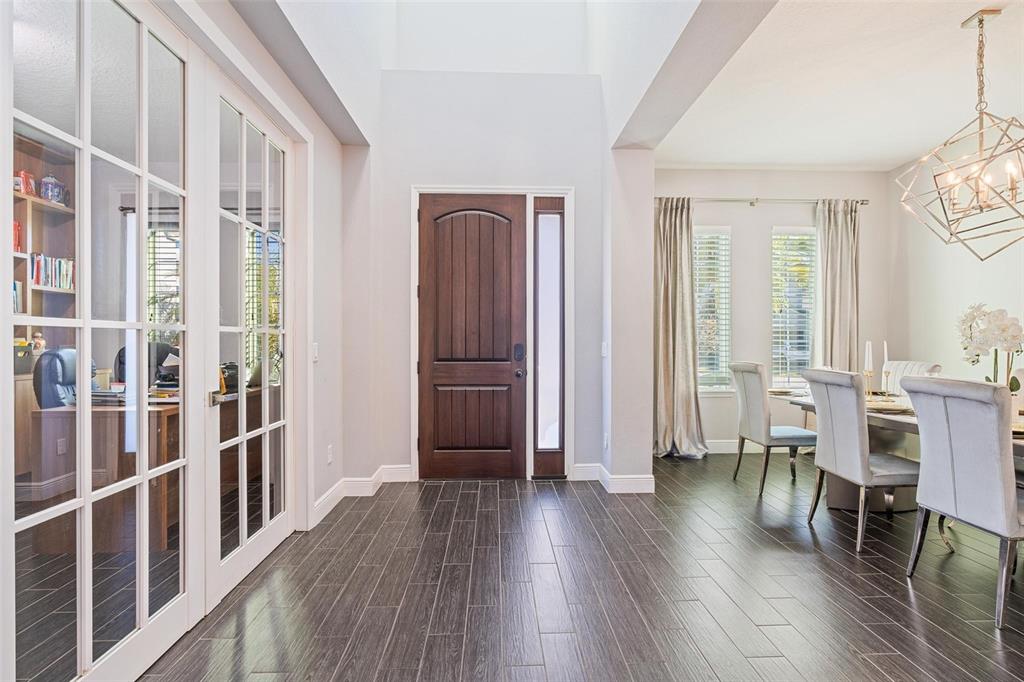 A bright entryway features dark wood-look tile flooring, a wooden front door, and French doors — 8324 LUDINGTON CIRCLE, ORLANDO, FL