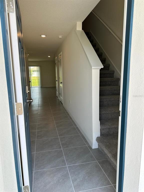 An entryway leads to a tiled hallway with a carpeted staircase and a rear sliding door — 2923 BRIE HAMMOCK BEND, ST CLOUD, FL