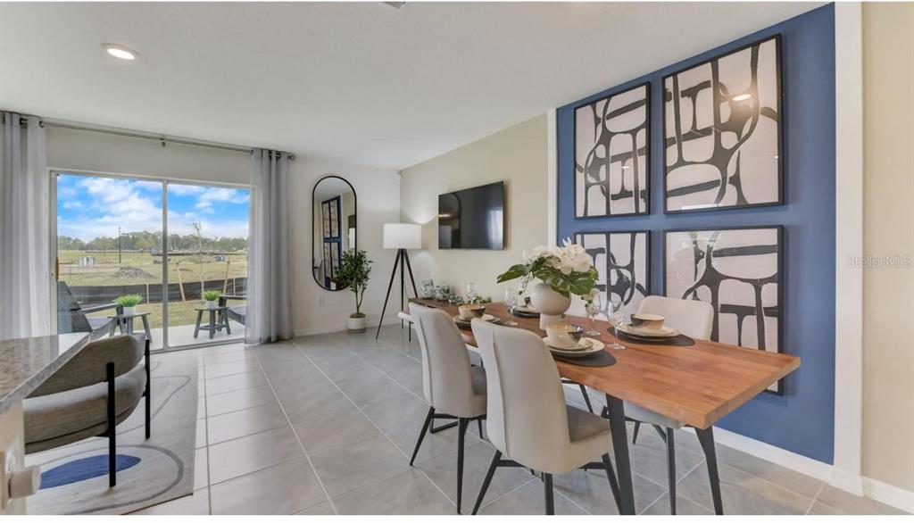 A dining room features a wooden table, light-colored chairs, and a blue accent wall — 2923 BRIE HAMMOCK BEND, ST CLOUD, FL