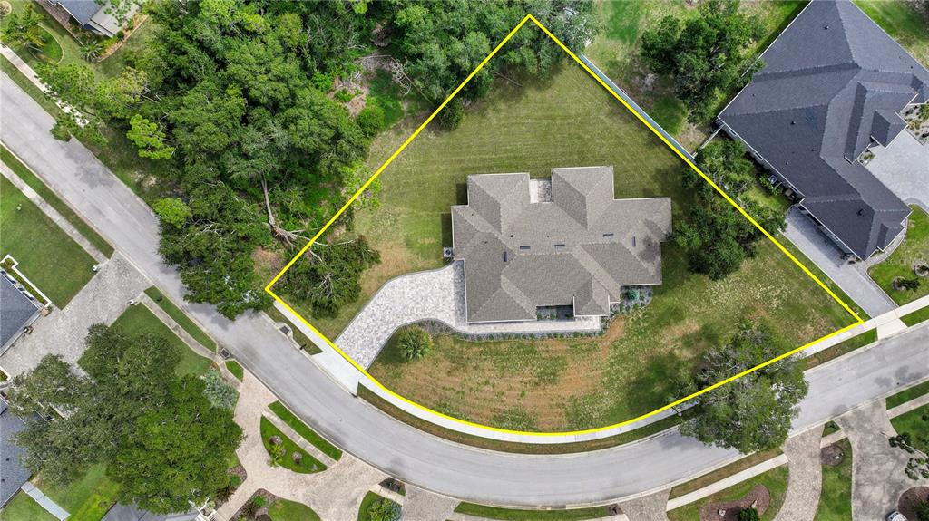 An aerial view shows a house with a paved driveway situated on a large corner lot — 9531 MID SUMMER LANE, LEESBURG, FL