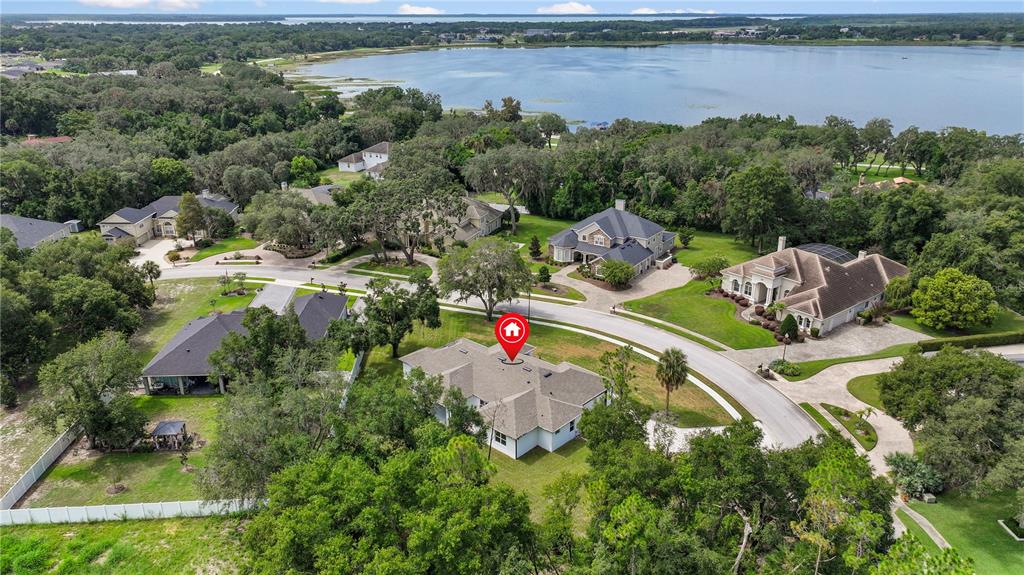 An aerial view shows a suburban house with a gray roof surrounded by trees and lawns — 9531 MID SUMMER LANE, LEESBURG, FL