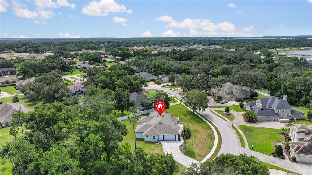 An aerial view shows a single-story house with a gray roof and paved driveway — 9531 MID SUMMER LANE, LEESBURG, FL