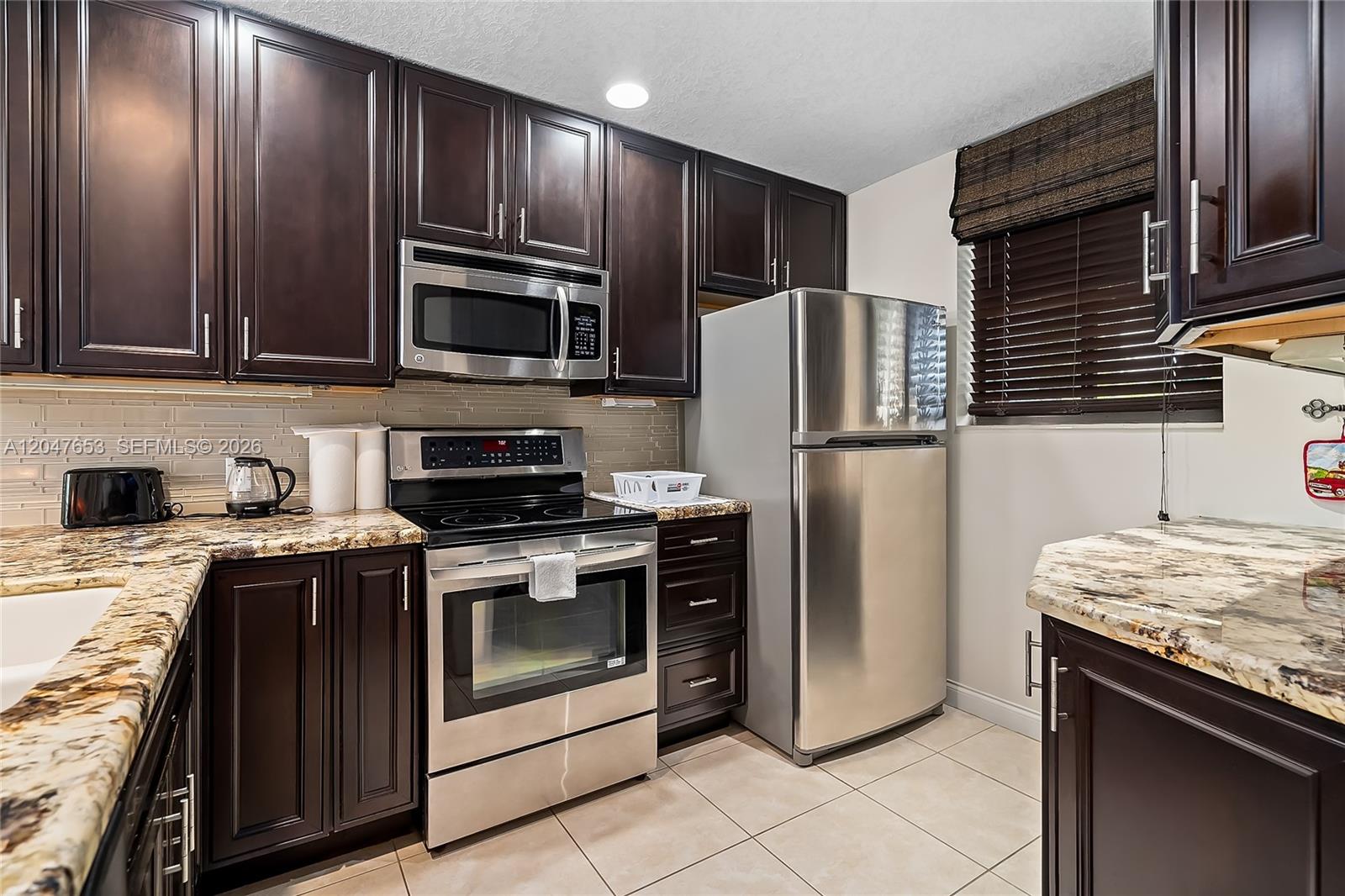 A kitchen features dark wood cabinets, stainless steel appliances, and granite countertops — 4345 Trevi Ct # 202, Lake Worth FL 33467, LAKE WORTH, FL