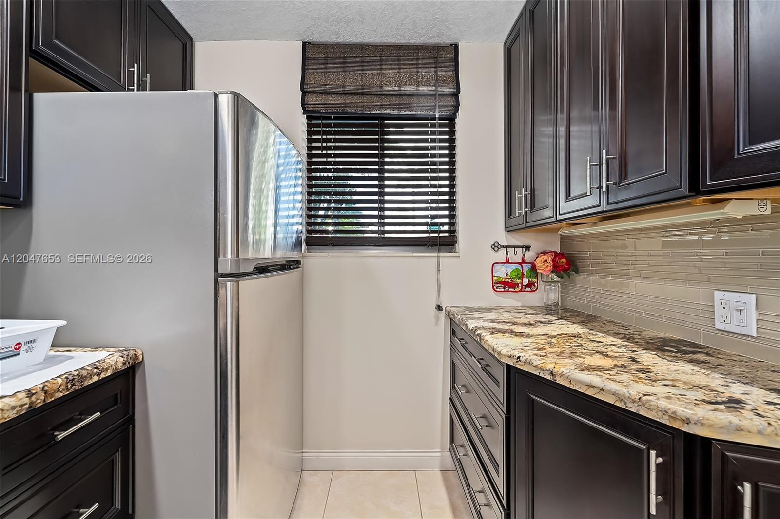 A kitchen features dark wood cabinets, granite countertops, stainless steel appliances, and a window with blinds — 4345 Trevi Ct # 202, Lake Worth FL 33467, LAKE WORTH, FL
