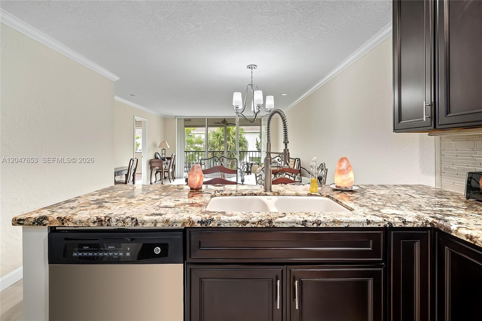A kitchen island with a double sink and granite countertop faces a dining area — 4345 Trevi Ct # 202, Lake Worth FL 33467, LAKE WORTH, FL