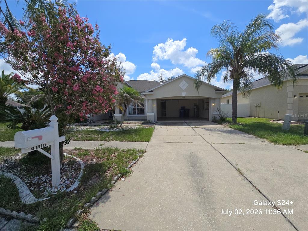 A single-story house with a concrete driveway, a two-car garage, and a flowering tree — 4106 BALINGTON DRIVE, VALRICO, FL