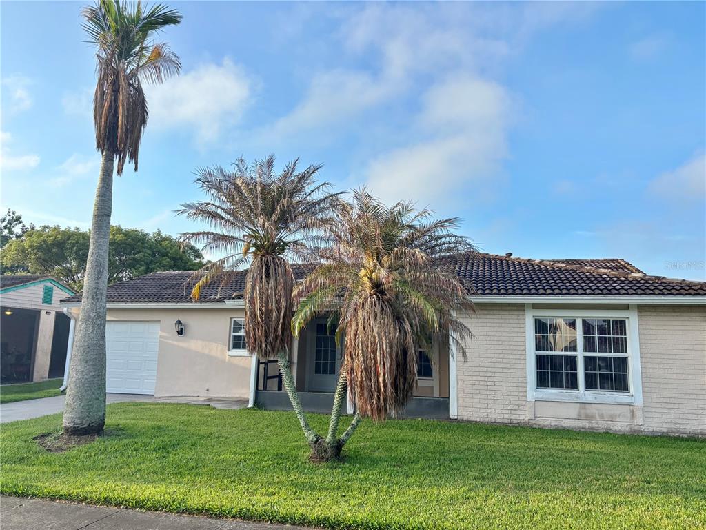 A single-story house with a brick facade, a tiled roof, and several palm trees — 5528 MINUTE MAN COURT, ORLANDO, FL