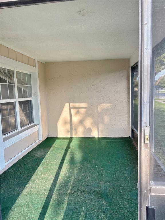 A screened-in porch features green outdoor carpeting, a textured beige wall, and a sliding door — 5528 MINUTE MAN COURT, ORLANDO, FL