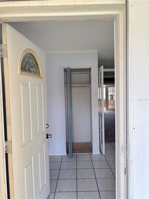 An entryway with a white front door, tiled floor, and an open closet — 5528 MINUTE MAN COURT, ORLANDO, FL