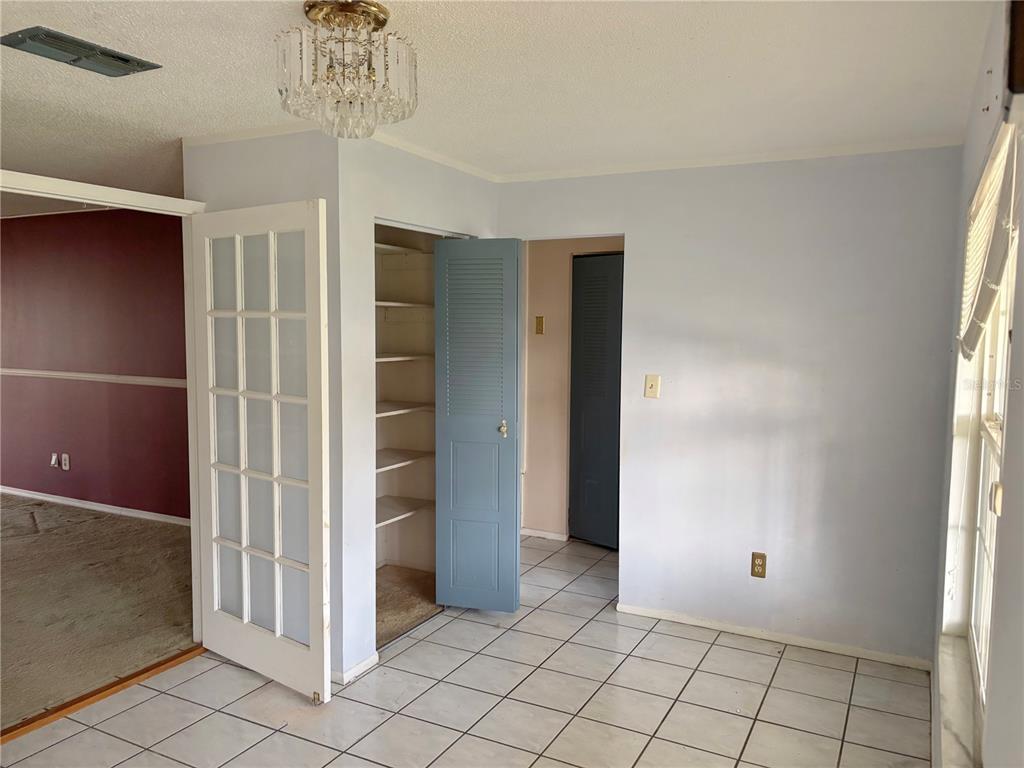 A room with white tile flooring, a crystal chandelier, and an open blue storage closet — 5528 MINUTE MAN COURT, ORLANDO, FL