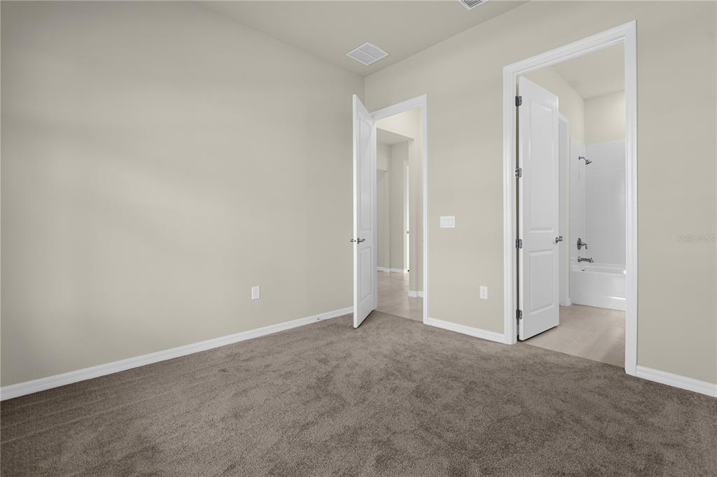 A carpeted bedroom features two open doorways leading to a hallway and a bathroom — 10411 PARK ESTATES AVENUE, ORLANDO, FL