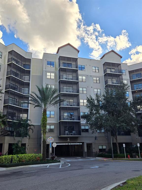 A multi-story apartment building with screened balconies and a ground-level parking garage entrance — 14501 GROVE RESORT AVENUE UNIT 3424, WINTER GARDEN, FL