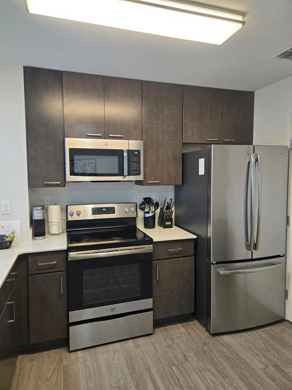 A kitchen features dark wood cabinets, stainless steel appliances, and light-colored countertops — 14501 GROVE RESORT AVENUE UNIT 3424, WINTER GARDEN, FL