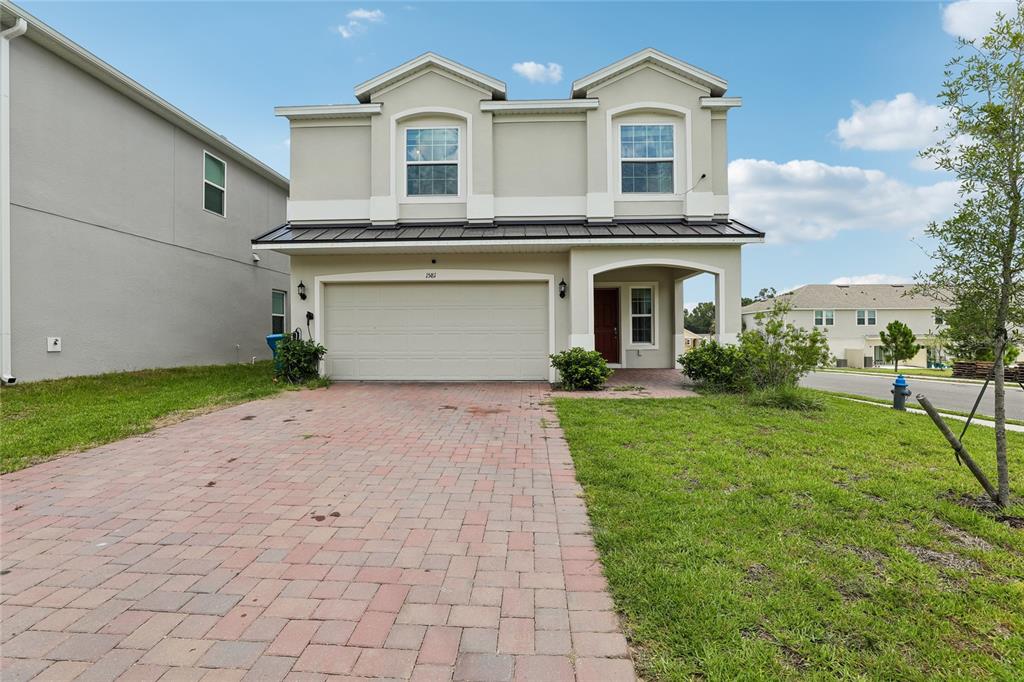 A two-story house with a paved driveway, a two-car garage, and a covered entryway — 1581 SWAN SWIM DRIVE, DAVENPORT, FL