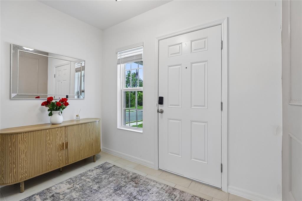 An entryway features a white door, a wood console table, a mirror, and a window — 1581 SWAN SWIM DRIVE, DAVENPORT, FL