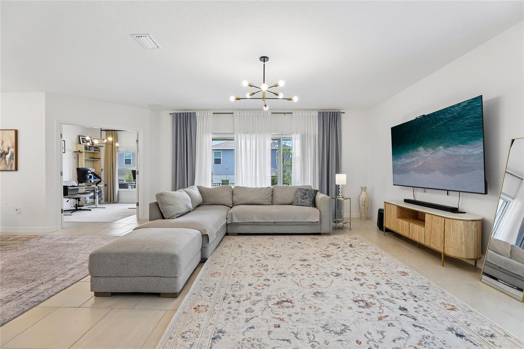 A living room features a large sectional sofa, a television, and a patterned area rug — 1581 SWAN SWIM DRIVE, DAVENPORT, FL