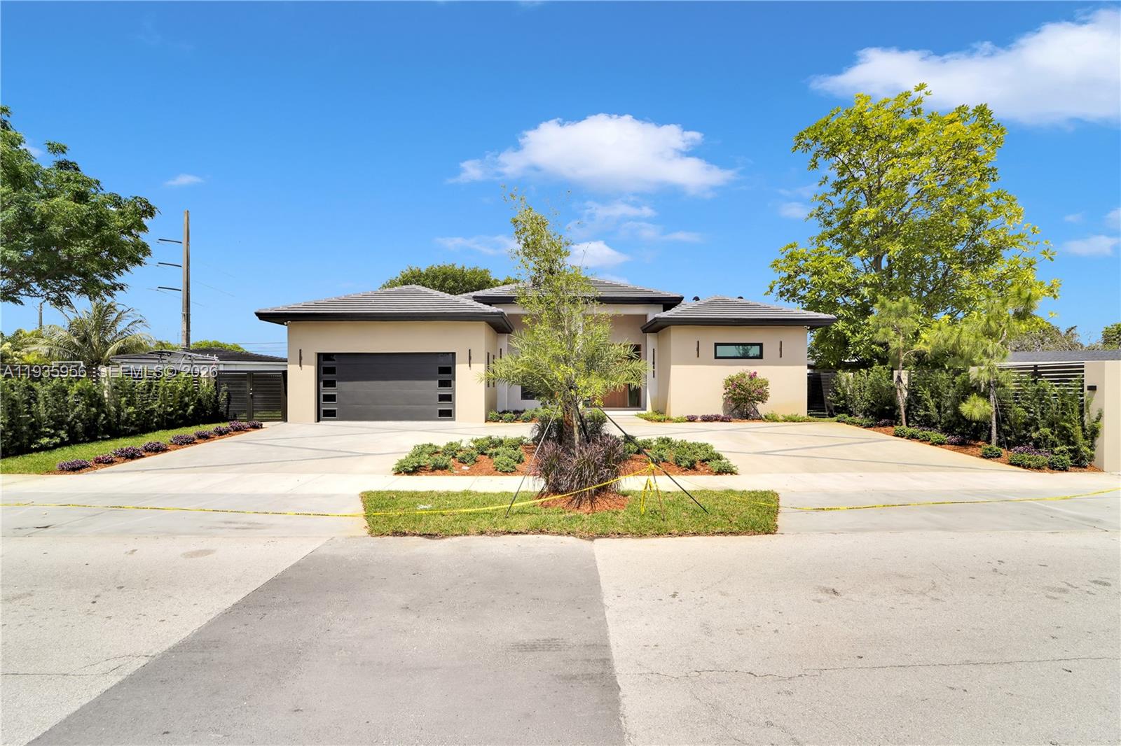 A modern single-story house features a two-car garage, a concrete driveway, and landscaped front gardens — 1130 SW 86th Ct, Miami FL 33144, MIAMI, FL