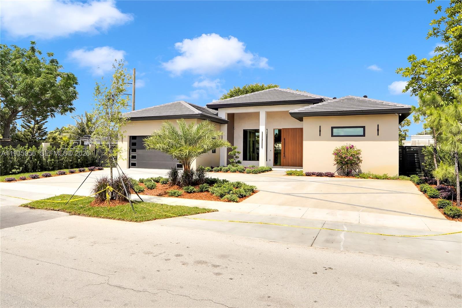 A modern single-story house with a gray tile roof, beige stucco walls, and a wooden door — 1130 SW 86th Ct, Miami FL 33144, MIAMI, FL