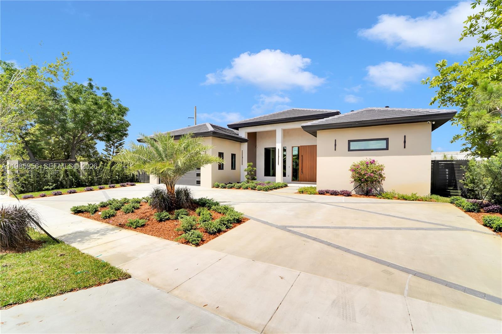 A modern single-story house features a concrete driveway, a palm tree, and a wooden door — 1130 SW 86th Ct, Miami FL 33144, MIAMI, FL