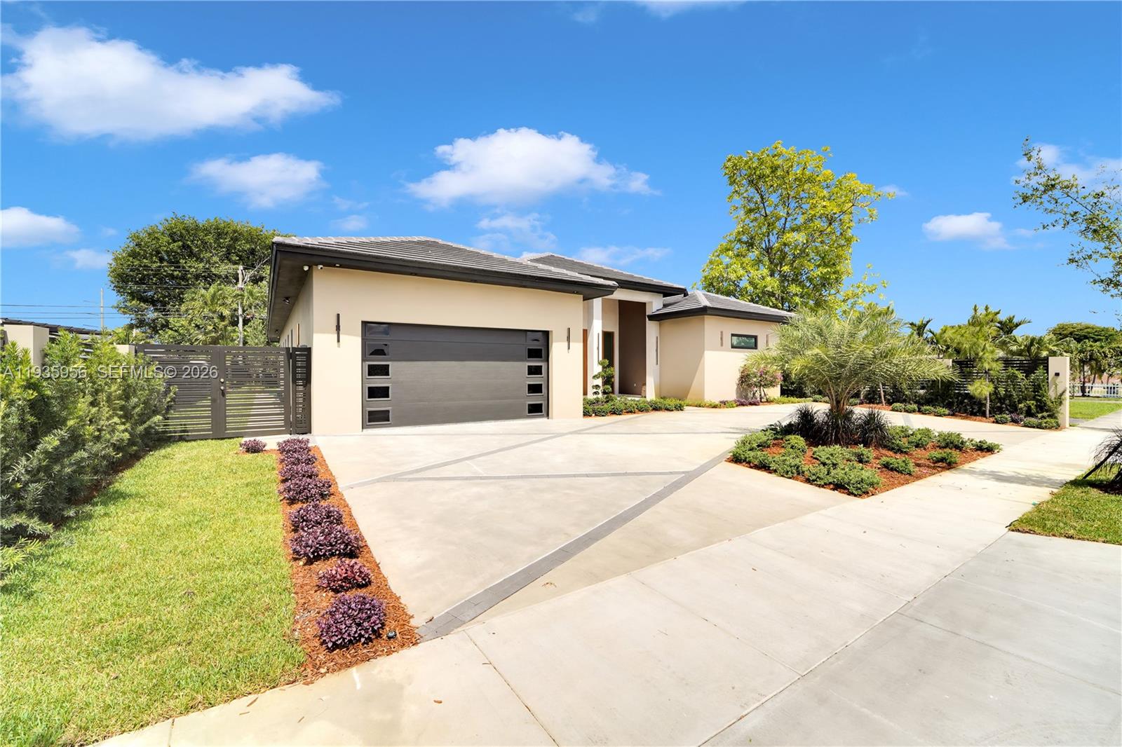 A modern single-story house features a dark garage door, concrete driveway, and landscaped front yard — 1130 SW 86th Ct, Miami FL 33144, MIAMI, FL