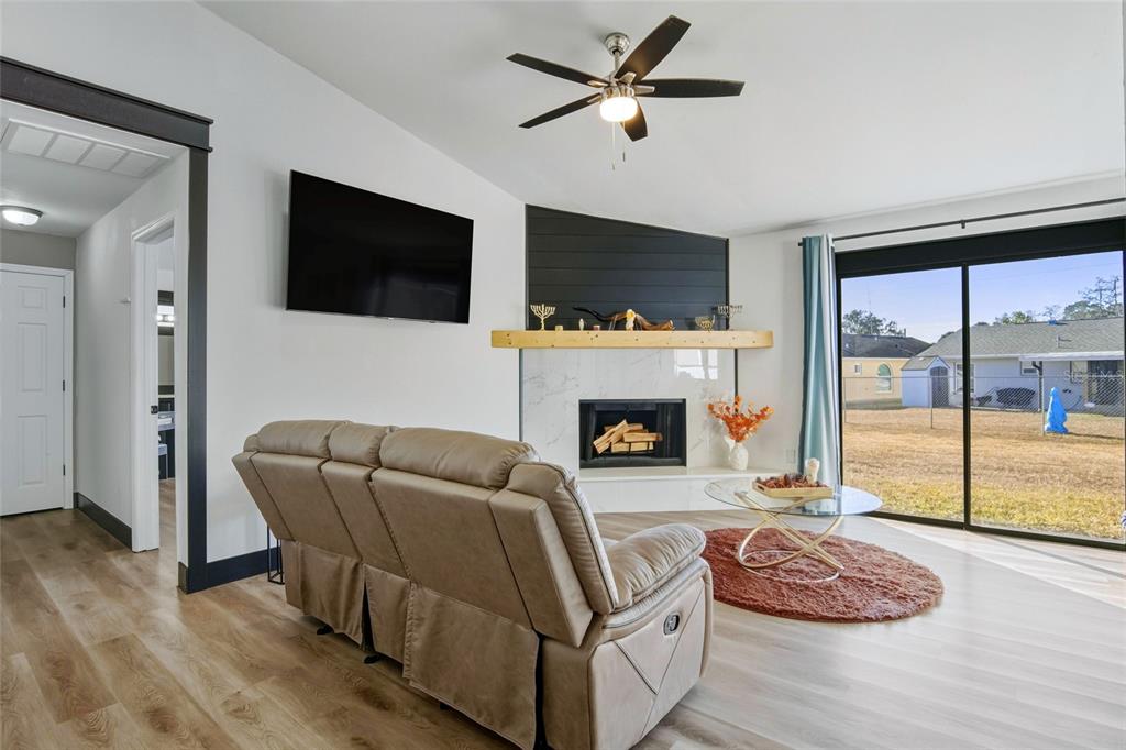 A living room features a fireplace with a wood mantel, a ceiling fan, and sliding doors — 114 DUNDEE LANE, KISSIMMEE, FL