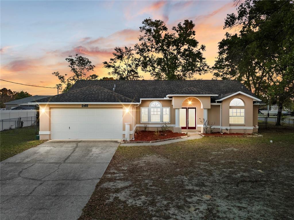A single-story house with a two-car garage, arched windows, and a covered front entryway — 10358 IRELAND STREET, SPRING HILL, FL