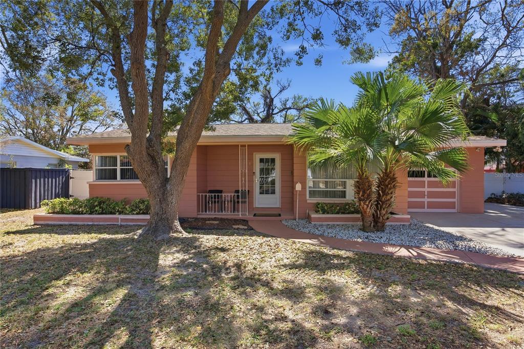 An empty living room features light wood flooring, teal accent walls, and a large window — 718 BAY VISTA BOULEVARD S, ST PETERSBURG, FL
