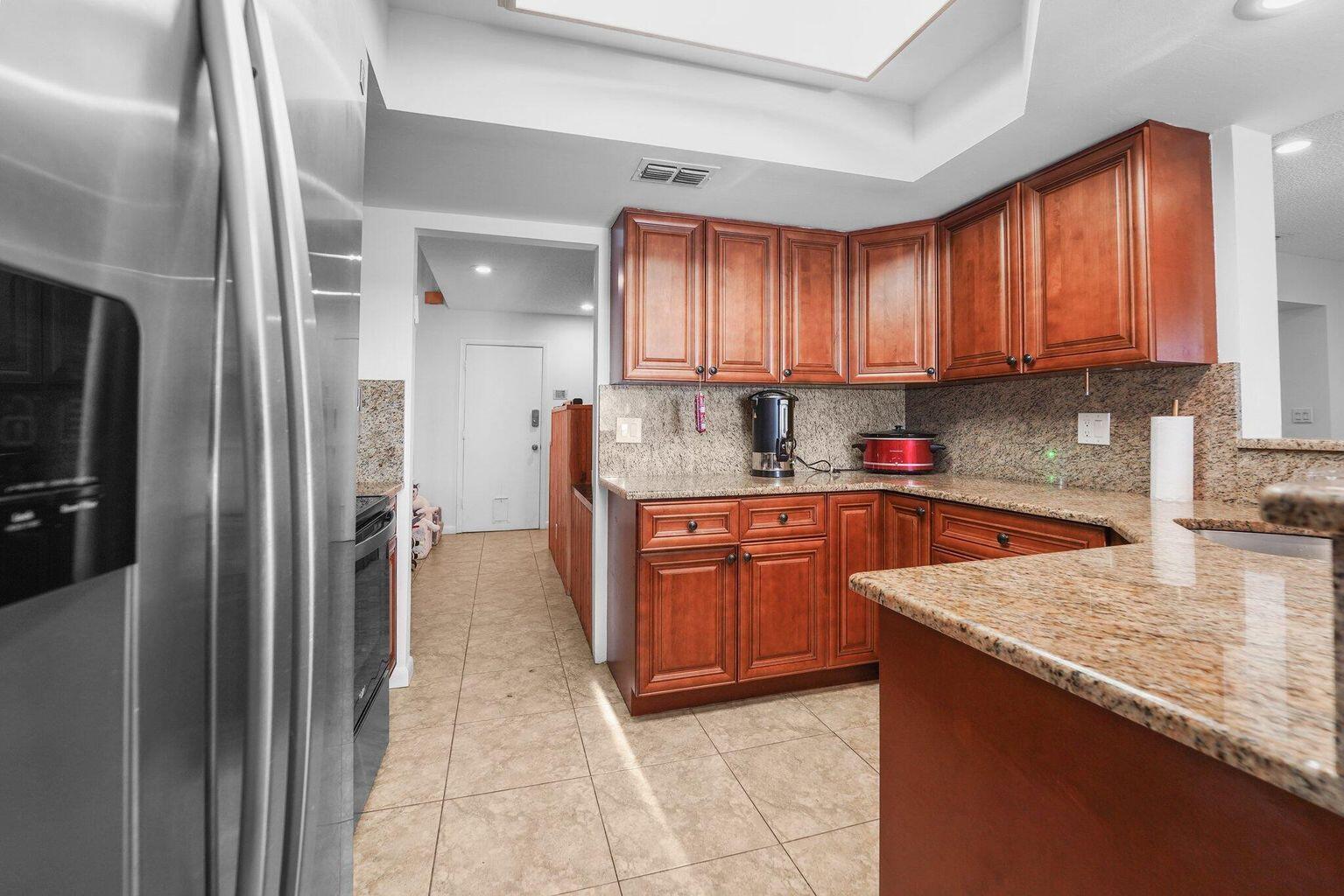 A kitchen with wood cabinets, granite countertops, and tile flooring — 6750 Boca Pines Trail # D, Boca Raton FL 33433, BOCA RATON, FL