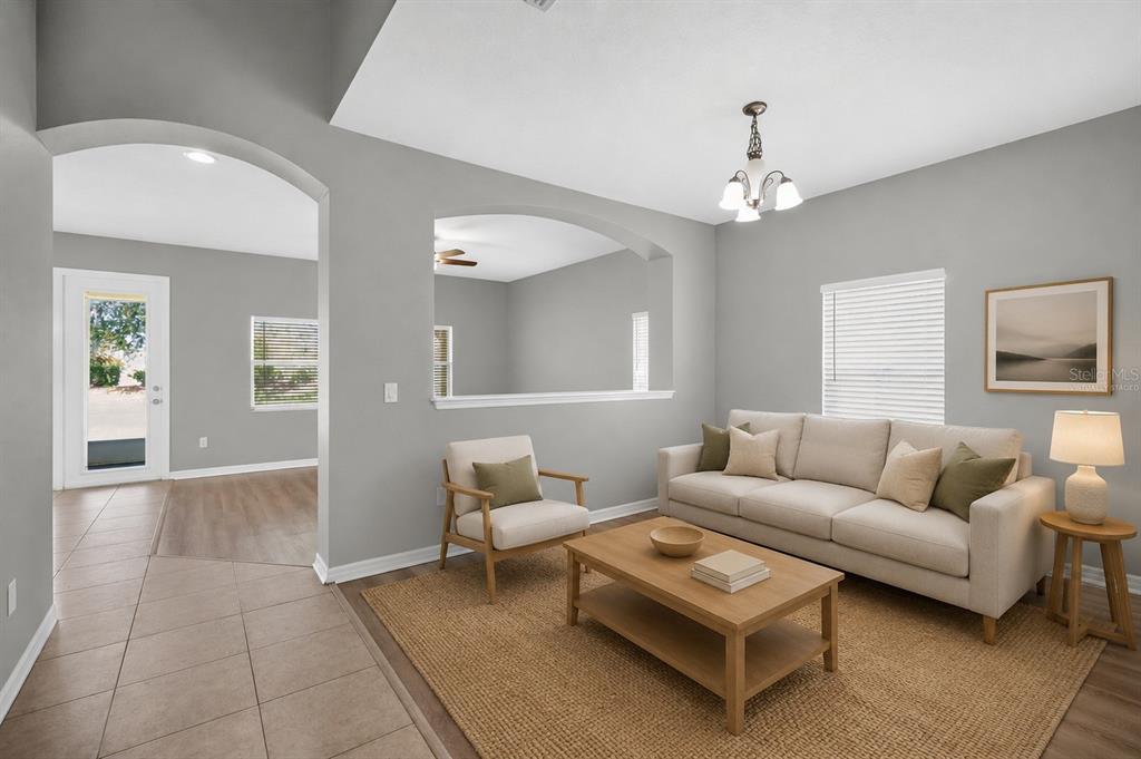 A living room with gray walls, tile flooring, a beige sofa, and an arched wall opening — 11144 ANCIENT FUTURES DRIVE, TAMPA, FL