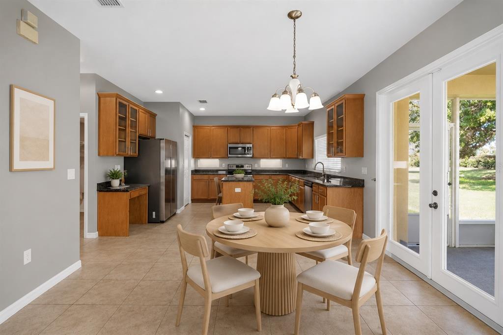 A kitchen and dining area with wood cabinets, dark countertops, and a round wooden table — 11144 ANCIENT FUTURES DRIVE, TAMPA, FL