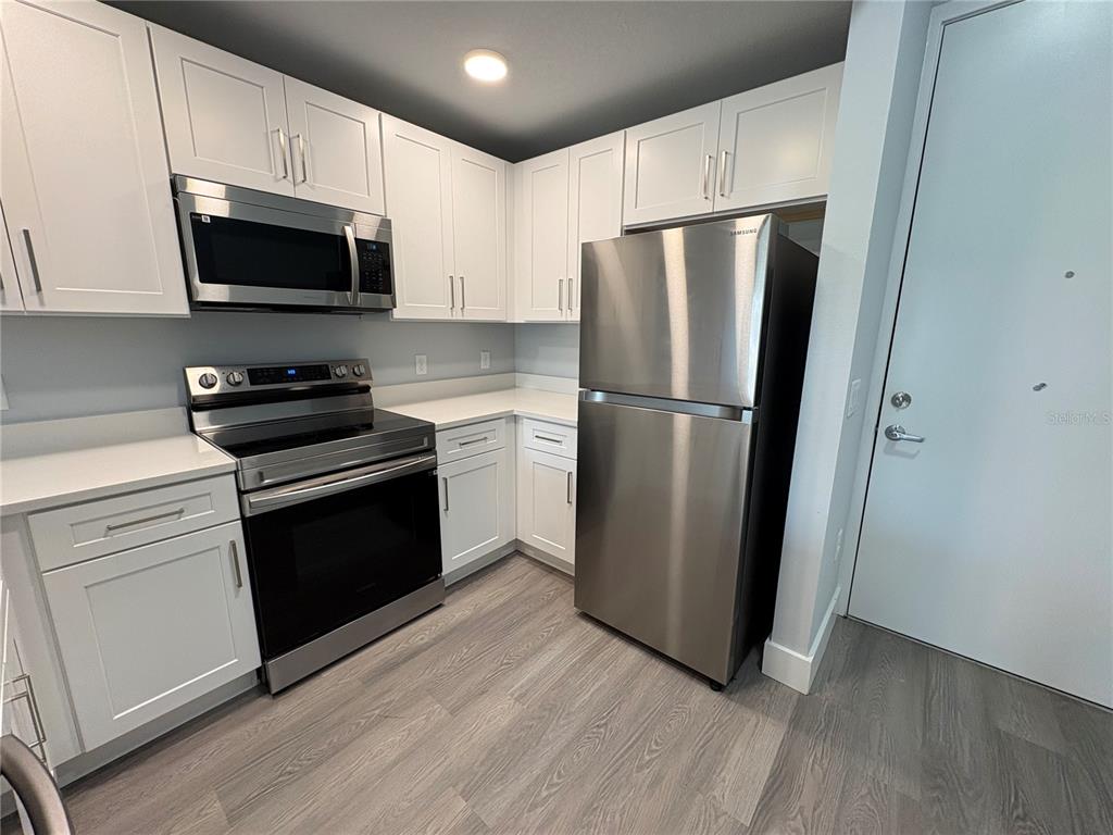 A kitchen features white cabinets, stainless steel appliances, and light wood-look flooring — 2240 FLORIDA DRIVE UNIT 101, DELTONA, FL