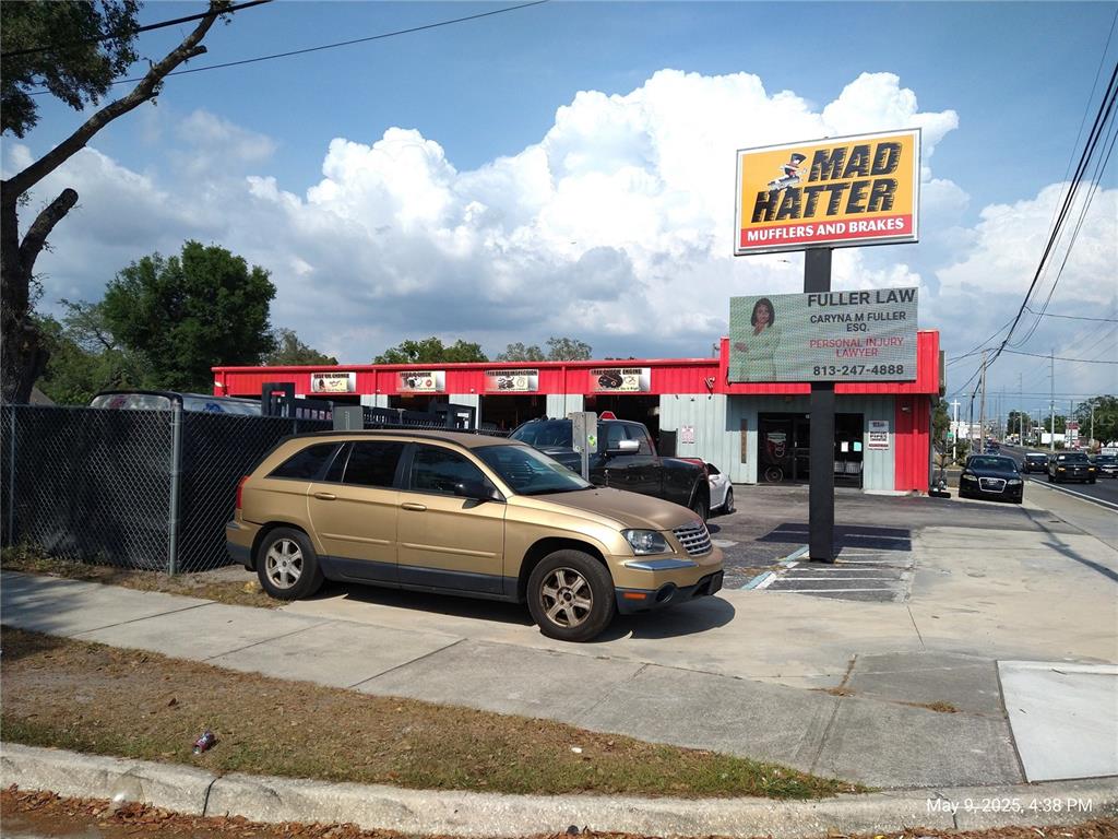 A gold SUV is parked in front of a Mad Hatter Mufflers and Brakes shop — 715 WEST WATERS AVENUE, TAMPA, FL