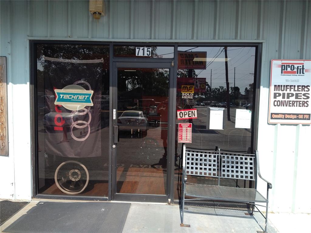 The exterior entrance of a commercial building features a glass door, signage, and a bench — 715 WEST WATERS AVENUE, TAMPA, FL