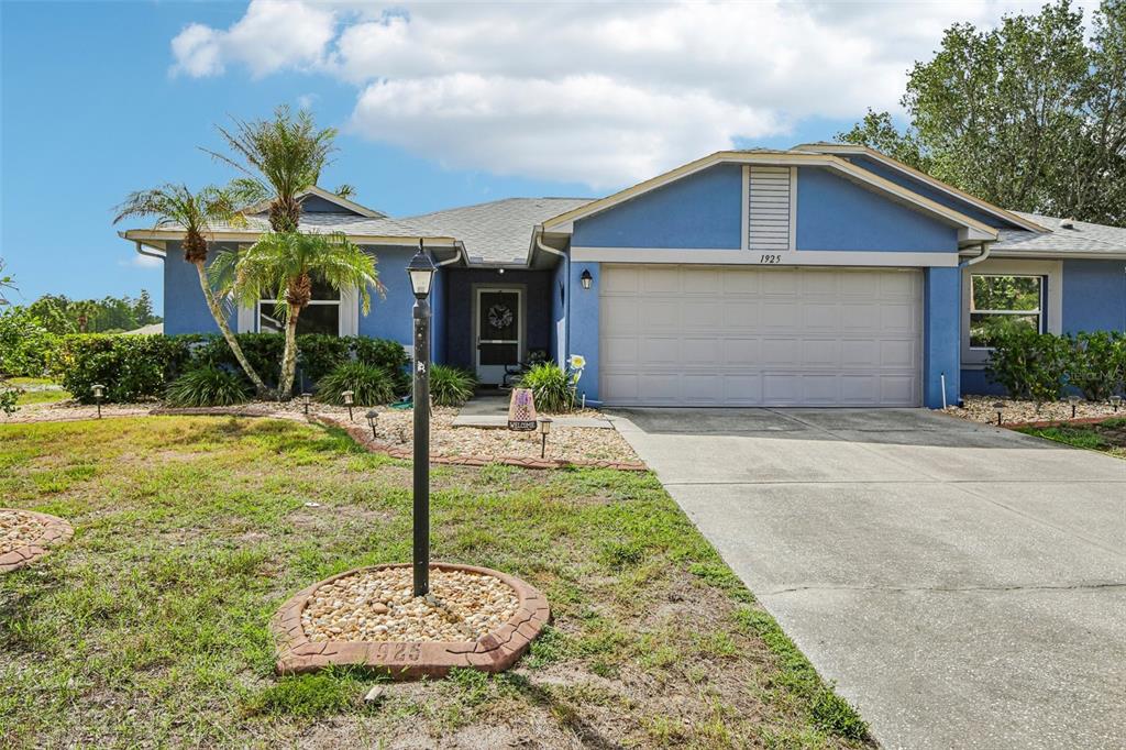 A blue single-story house with a two-car garage, a palm tree, and a concrete driveway — 1925 GRAND CYPRESS LANE, SUN CITY CENTER, FL