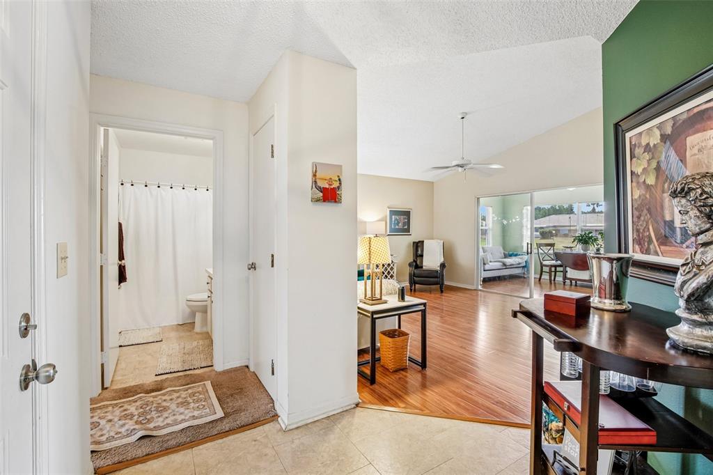 An entryway with tile flooring leads to a bathroom on the left and a living area — 1925 GRAND CYPRESS LANE, SUN CITY CENTER, FL